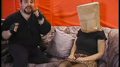 Une pute joufflue avec un sac en papier sur la tête a ses seins et sa chatte