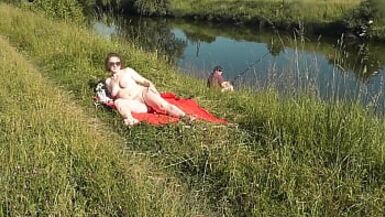 MILF sexy Frina on river bank undressed and sunbathes naked. Random man fisherman watching for her, and in the end decided to join naked woman. Wild beach. Nudist beach. Public nudity. Public exposure. Naked in public - 1 image